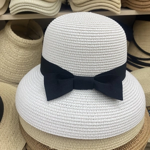 Detailed view of the white woven straw hat texture with a wide black grosgrain ribbon bow