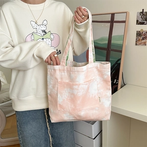 Dettaglio della borsa tote in tela tie-dye rosa con tasca frontale e etichetta Zakka