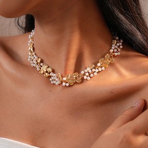 Close-up of elegant gold leaf necklace with white pearls on a model neck in retro style