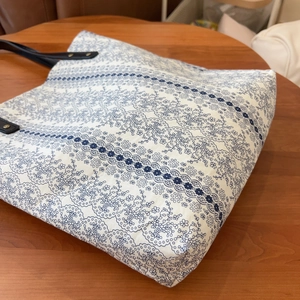 Close-up of floral cotton tote bag with blue patterns and black leather handles