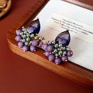 Detailed shot of teardrop zircon earrings with blue and purple beads on retro background