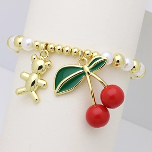 Close-up of pearl bead bracelet featuring a golden bear and red enamel cherry charm