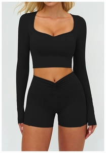 Détail d'ensemble de yoga noir avec haut court à manches longues et short plissé taille haute