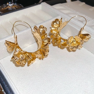Detailed view of layered golden ginkgo leaf earrings inside a premium jewelry gift box