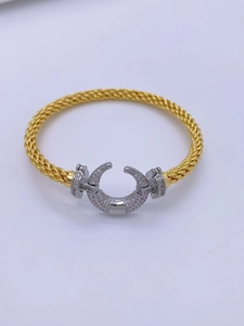 Close-up of gold braided bangle with a horseshoe clasp pavé-set with sparkling crystals