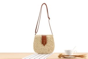 Detailed close-up of beige paper rope woven bag with brown PU leather flap and strap