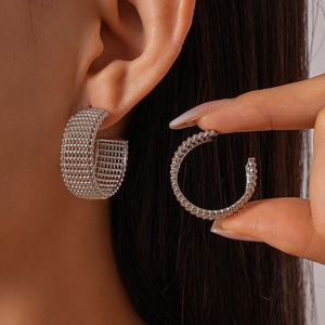 Silver geometric C-shaped hoop earrings with grid texture shown on model ear