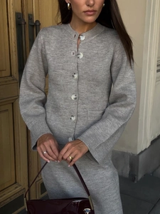 Detail of grey knitted two-piece set featuring a buttoned cardigan and matching midi skirt