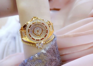 Close-up of luxury gold women's watch with crystals and a butterfly charm bracelet