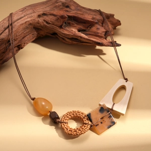Dettaglio di collana boho con perle in resina, anello in vimini e pendente in acrilico