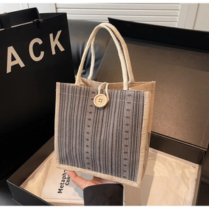 Detailed macro view of linen tote bag with rope handle and large wooden button in a gift box