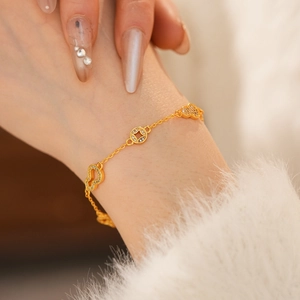 Detail of 24k gold-plated bracelet with zircon hulu and coin charms on woman wrist