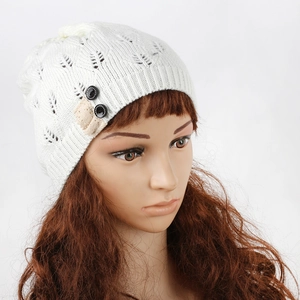 Close-up of white knitted beanie hat with hollow leaf pattern and lace button detail