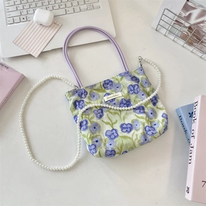 Dettaglio borsa in tela floreale con manici viola e tracolla di perle di tendenza