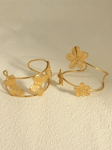 Macro detail of 18k gold plated stainless steel bangles with flower and butterfly engraving