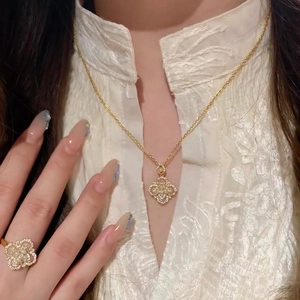 Detail of clover necklace and ring set with pearls and zircons on elegant female model