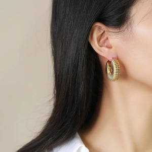 Macro view of C-shaped 18K gold-plated titanium earrings with textured spiral thread finish