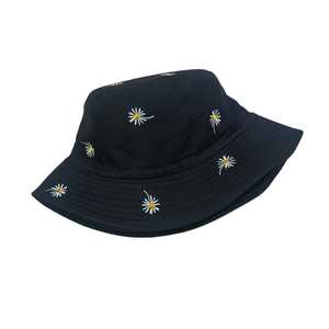 Detailed close-up of white daisy embroidery on a black cotton bucket hat surface