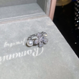Close-up of zircon-encrusted flower ear cuff with white freshwater pearl on velvet