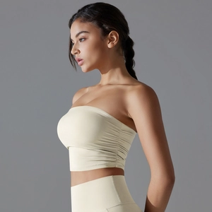 Detail view of cream ruched sports bra showing side pleated texture and high-stretch fabric