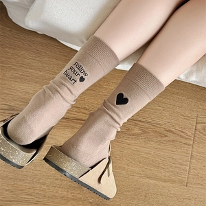 Detailed close-up of khaki mid-calf socks with heart embroidery and follow your heart text