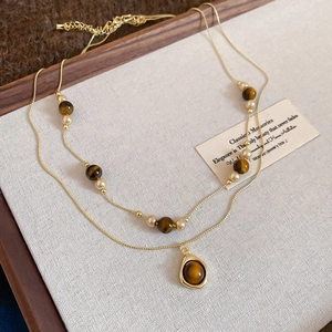 Detail of vintage double-layer gold necklace with tiger eye beads and water drop pendant