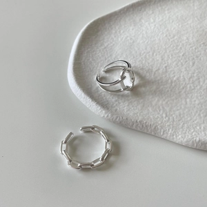Macro shot of interlocking geometric 925 sterling silver chain rings on white ceramic base