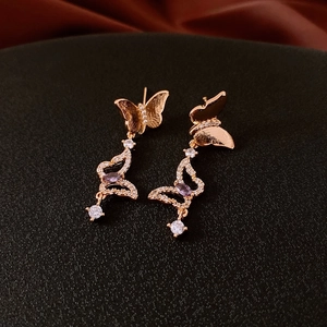 Close-up of gold butterfly earrings with purple gems and delicate zircon tassels