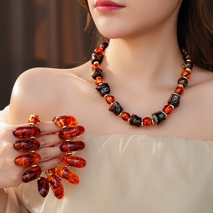 Close-up of amber resin bead necklace and matching large bracelet on a female model