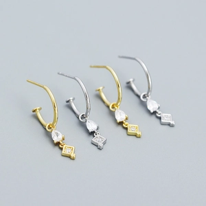 Detail of s925 silver stud earrings with teardrop zircons and geometric pendants