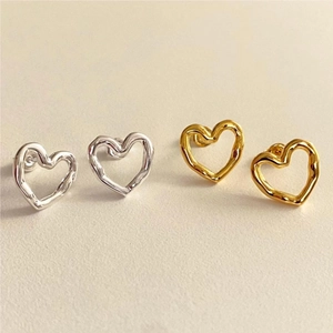 Detail of irregular hollow heart stud earrings in gold and silver with liquid metal texture