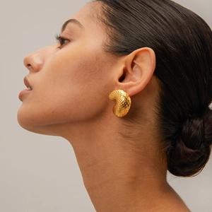 Detail of a 18k gold plated curved earring with fish scale texture on a model