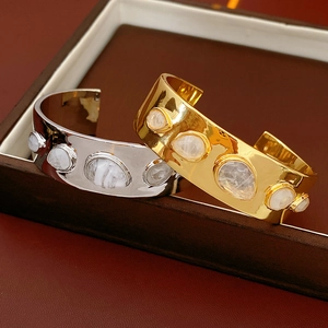 Détail de bracelets manchettes martelés en or et argent avec pierres blanches translucides