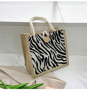 Close-up of zebra print canvas tote bag with cotton rope handles and wooden button detail