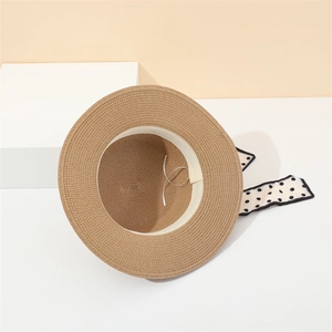 Detail of straw sun hat featuring polka dot ribbon and adjustable inner drawstring