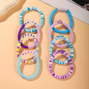 Detail of colorful polymer clay bead bracelets with SMILE and LOVE charms on apricot background