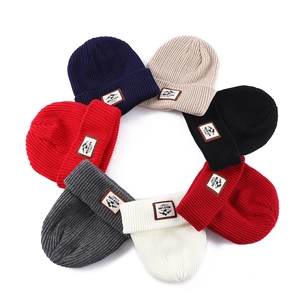 Winter-Strickmützen in vielen Farben mit Leder-Logo-Patch auf weißem Hintergrund