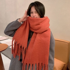 Soft orange mohair scarf with fringe detail shown on a model in a cozy indoor setting