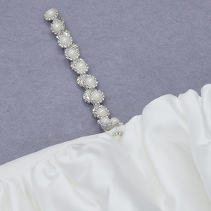 Detailed view of white satin dress with luxury faux pearl and rhinestone straps