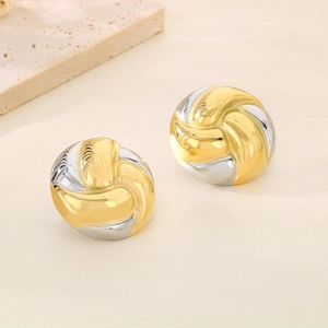 Gros plan de boucles d'oreilles nœuds bicolores or et argent sur lin texturé