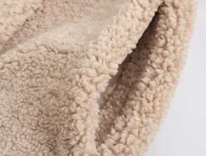 Gros plan détaillé d'une veste en polaire beige montrant les coutures de la poche