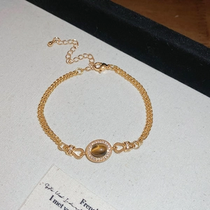 Détail du bracelet doré avec une pierre oeil de tigre ovale et bordure en cristaux