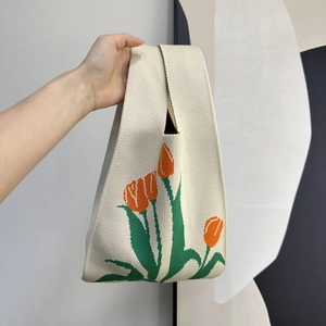 Close-up of knit tote bag with orange tulip flower pattern and textured cream fabric