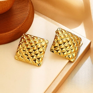Gros plan de boucles d'oreilles carrées dorées avec motif géométrique matelassé