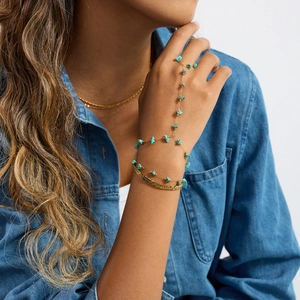 Detail of bohemian gold-plated slave bracelet with turquoise stones on a denim shirt