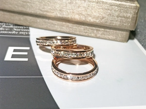 Close-up of three stacked eternity rings in rose gold with channel-set princess cut cubic zirconia
