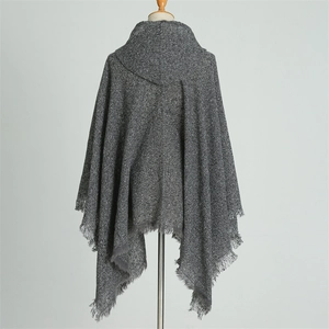 Detail of grey hooded poncho wrap with elegant fringe edges and soft knit texture
