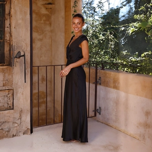 Elegant black satin maxi dress with V-neckline and waist-slimming fit shown in a profile view
