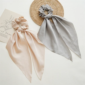 Detail of satin ponytail holders with long streamers in champagne and light grey colors