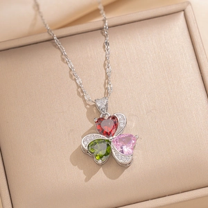 Close-up of a clover pendant with red, green, and pink heart stones on a silver chain